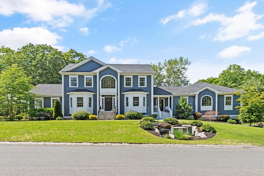 a front view of a house with a garden and trees