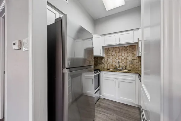 a kitchen with a refrigerator and white cabinets