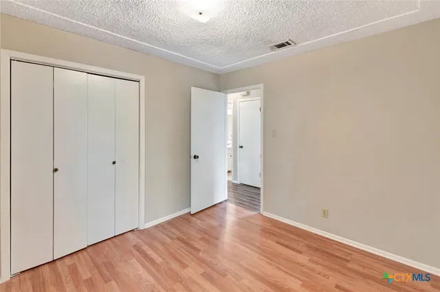 a view of a big room with wooden floor and a window
