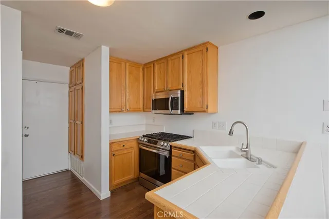 a kitchen with stainless steel appliances a sink dishwasher a refrigerator and cabinets with wooden floor