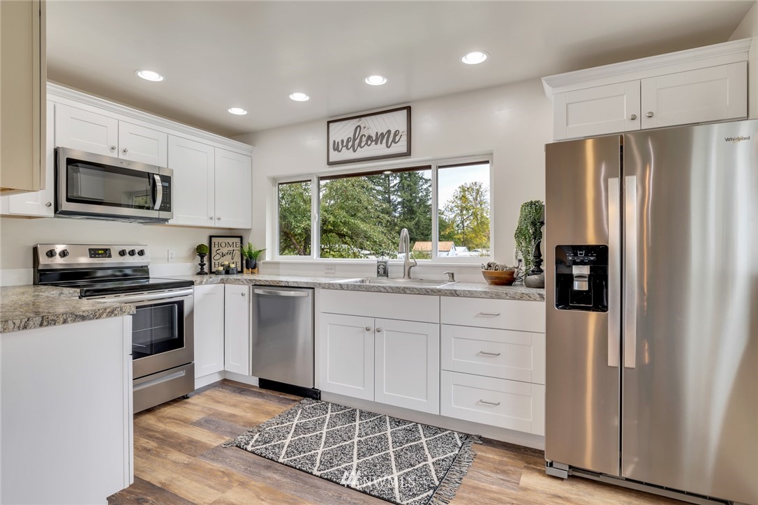 20260 Maxwell Road Southeast Maple Valley, WA 98038 - Photo 10 of 38 a kitchen with stainless steel appliances granite countertop a refrigerator sink and stove