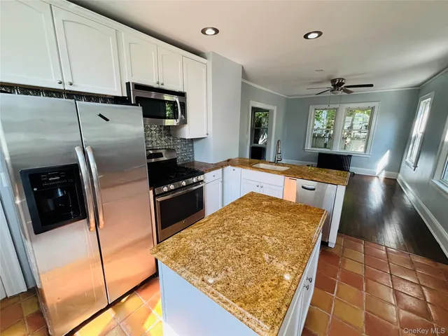 a kitchen with stainless steel appliances granite countertop a refrigerator stove top oven dining table and chairs