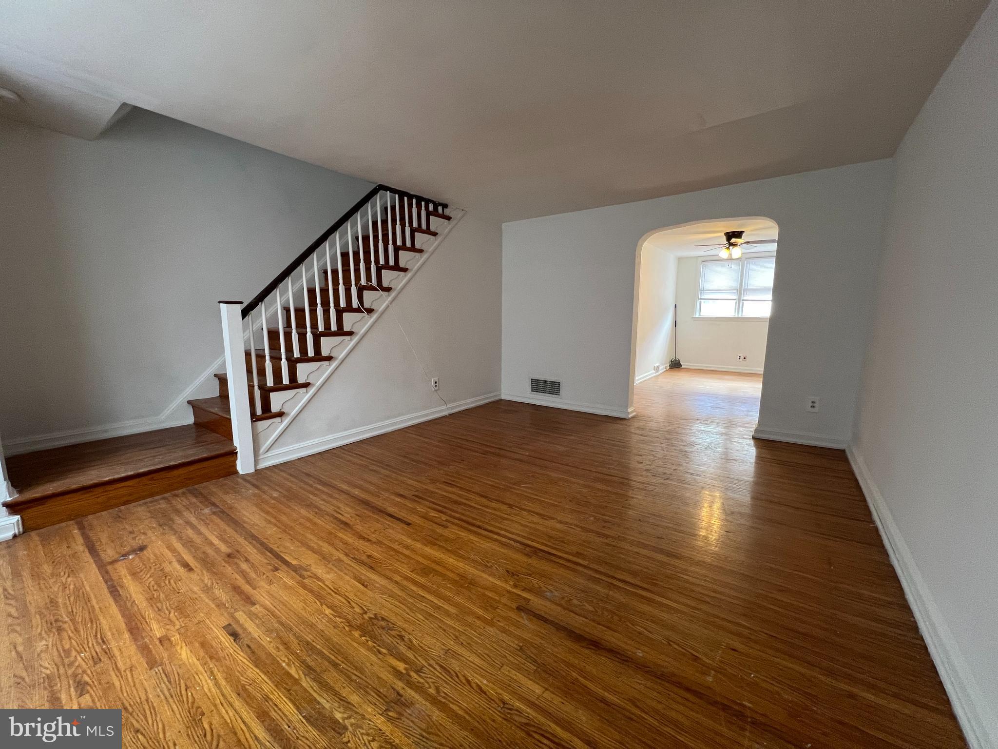 a view of an empty room with wooden floor and stairs