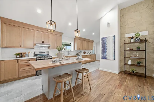 a kitchen with a sink a stove cabinets and wooden floor