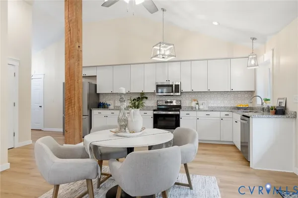 a kitchen with stainless steel appliances kitchen island granite countertop a table chairs microwave and sink