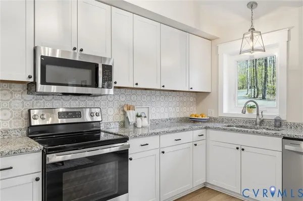 a kitchen with granite countertop white cabinets and appliances