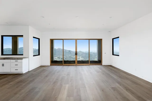 a view of an empty room with window and wooden floor