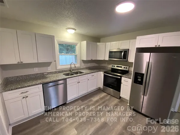 a kitchen with granite countertop a refrigerator and a sink