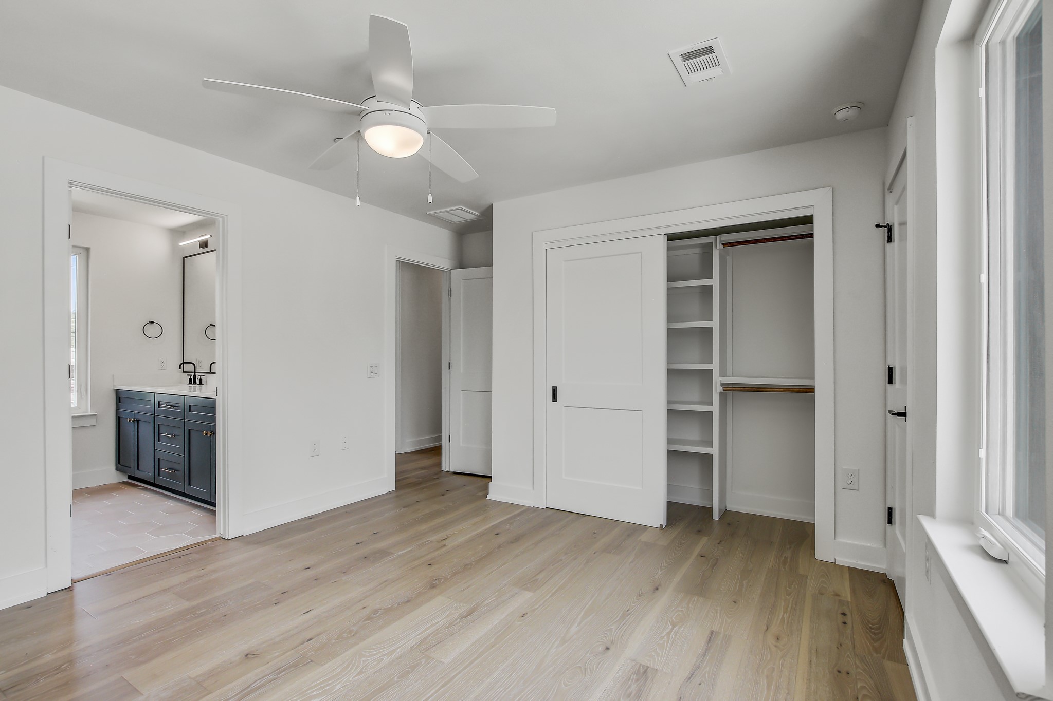 4127 East 12th Street, Unit 5 Austin, TX 78721 - Photo 20 of 33 Unfurnished bedroom featuring light wood-style floors, a closet, ensuite bathroom, and a sink