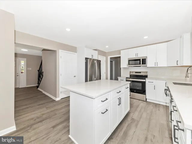 a kitchen with stainless steel appliances kitchen island granite countertop a stove a sink and a refrigerator