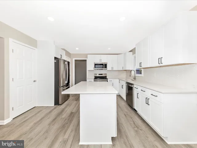 a kitchen with a refrigerator a stove top oven and white cabinets
