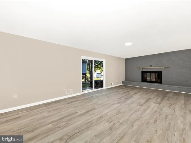 a view of empty room with wooden floor and window