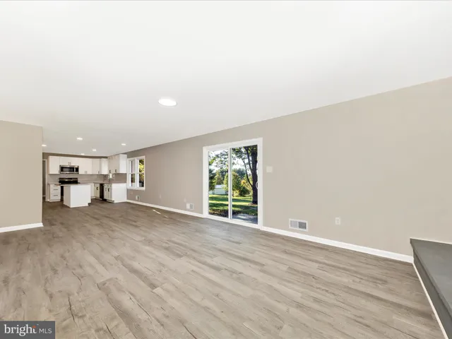 a view of empty room with wooden floor and window