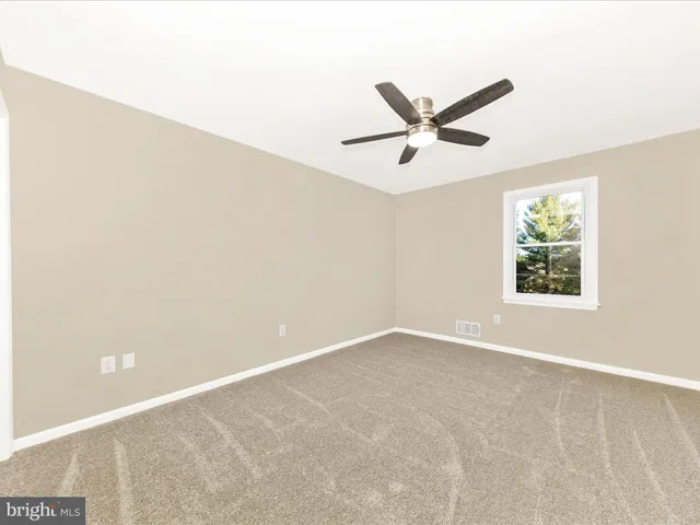 an empty room with a window and a fan