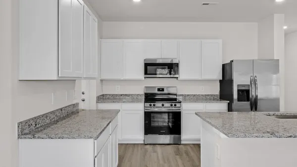 a kitchen with granite countertop a sink stove and refrigerator