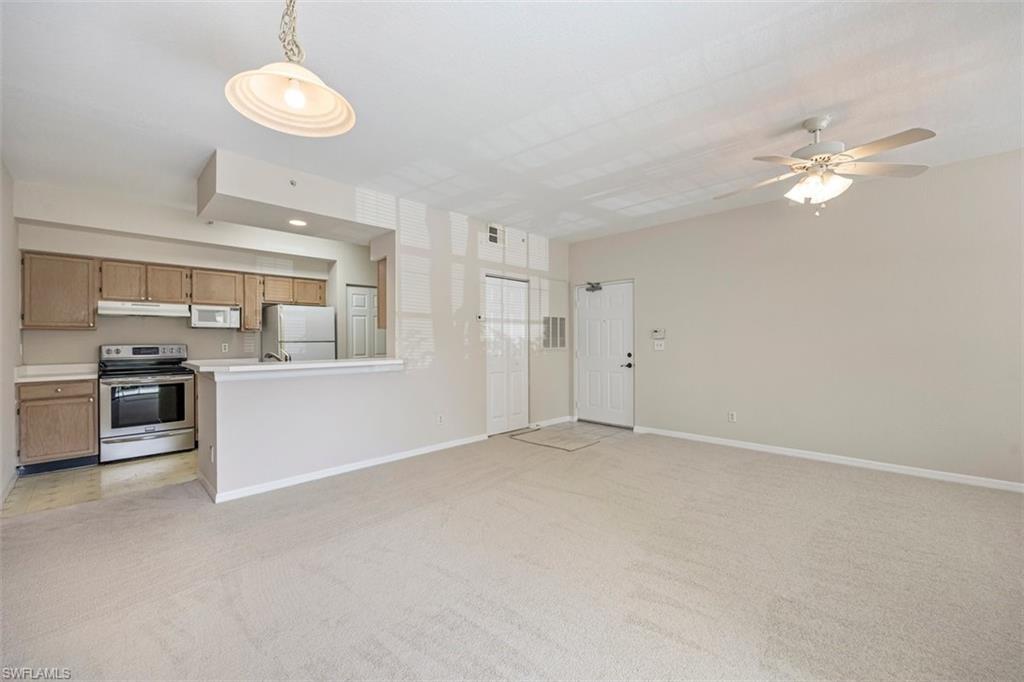 4635 St Croix Lane, Unit 1218 Naples, FL 34109 - Photo 8 of 40 Unfurnished living room with light colored carpet and a ceiling fan