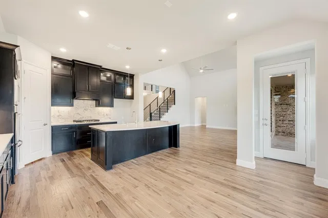 a large room with kitchen island stainless steel appliances wooden floor and living room view