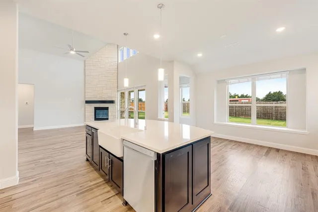 a large kitchen with kitchen island a stove a sink a refrigerator and wooden floor