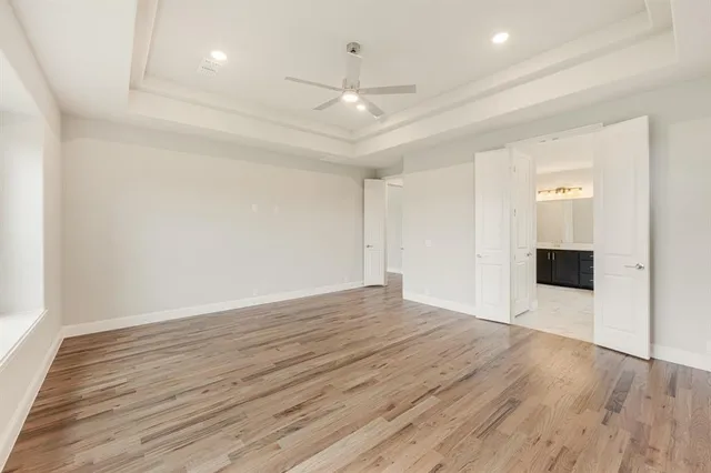 an empty room with wooden floor and ceiling fan