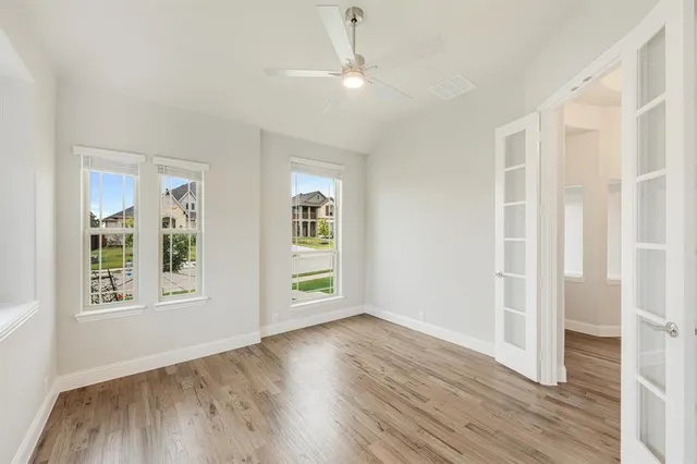 an empty room with wooden floor and windows