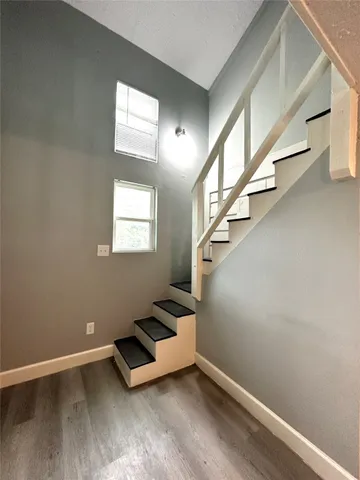 a view of an empty room with wooden floor and stairs