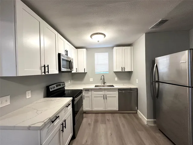 a kitchen with a sink a refrigerator and white cabinets