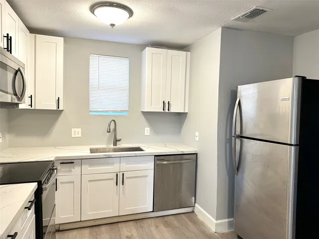 a kitchen with a refrigerator sink and cabinets