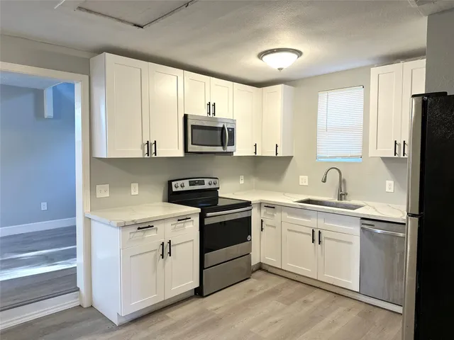 a kitchen with appliances a sink and cabinets