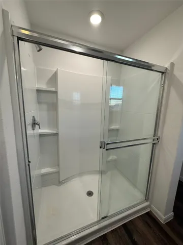 a bathroom with a glass shower door and a window