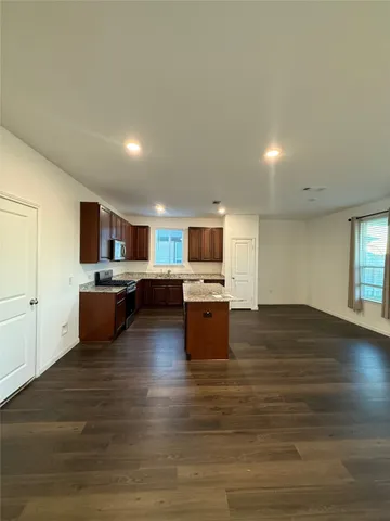 a open kitchen with kitchen island a sink dishwasher stove with wooden floors