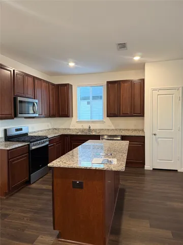 a kitchen with stainless steel appliances granite countertop wooden cabinets a refrigerator and a stove