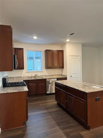 a large kitchen with stainless steel appliances granite countertop a stove a sink dishwasher and a refrigerator