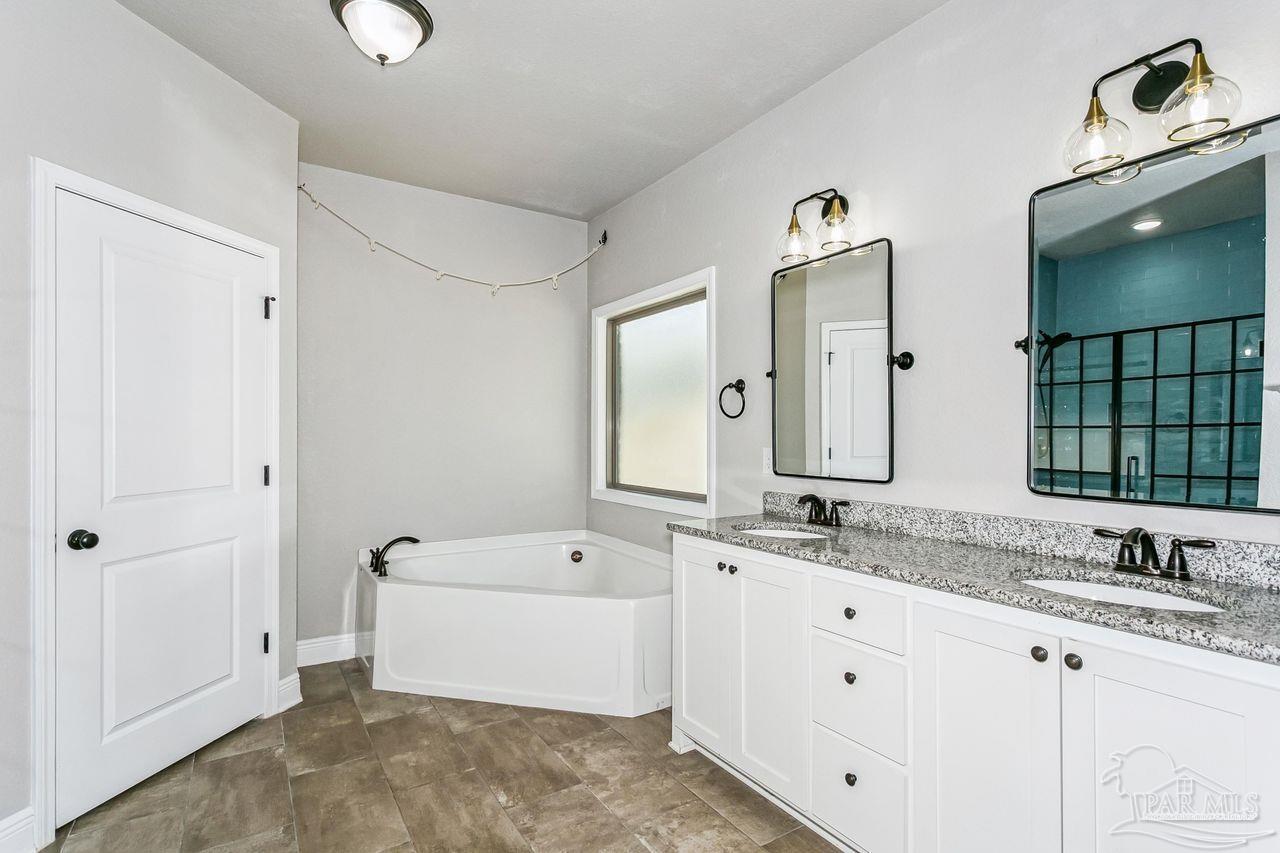 3875 Shady Grove Drive Pace, FL 32571 - Photo 18 of 31 a bathroom with double vanity sinks a large mirror and a bathtub