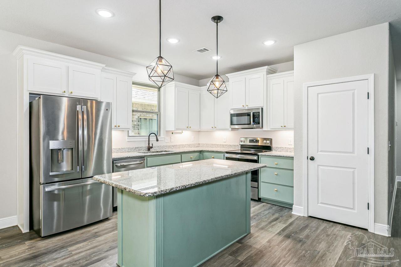 3875 Shady Grove Drive Pace, FL 32571 - Photo 10 of 31 a kitchen with granite countertop a refrigerator a sink a stove and wooden floors