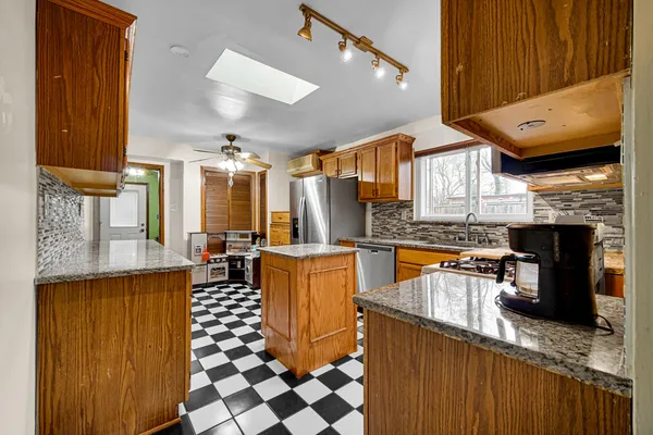 a kitchen with stainless steel appliances granite countertop a stove a sink dishwasher and a refrigerator with wooden cabinets