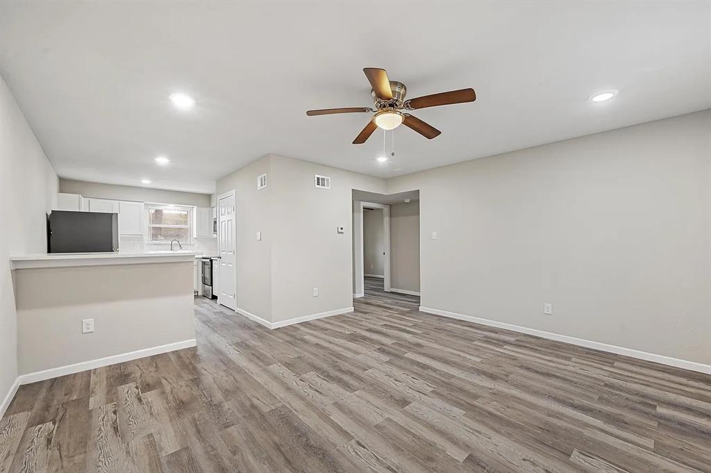 Spacious room featuring wood-finish flooring, recessed lighting, and a ceiling fan
