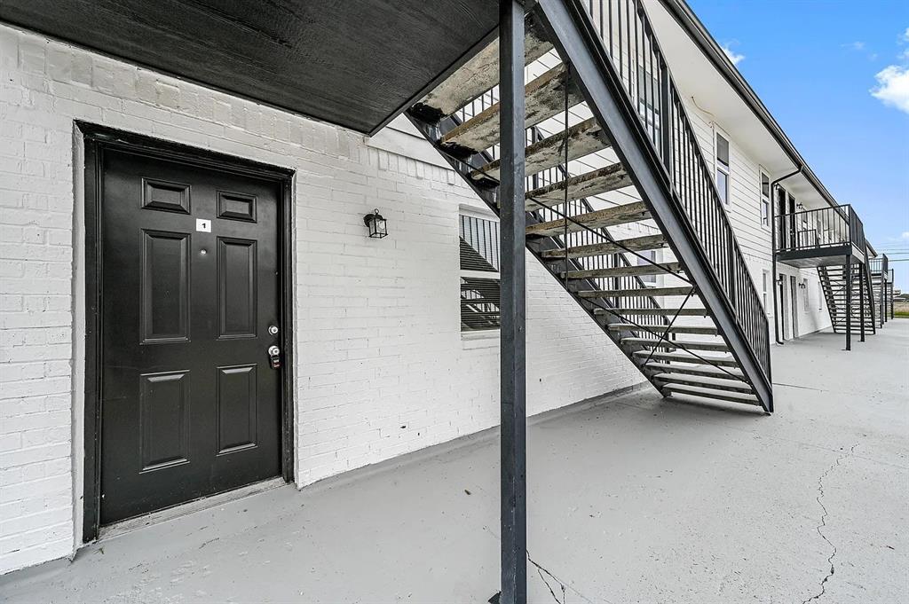 500 Highway 75, Unit 35 Van Alstyne, TX 75495 - Photo 11 of 12 Exterior featuring white painted brick, a black paneled entry door, black exterior lighting, and a black metal staircase with railings