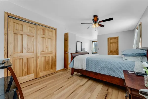 a bedroom with a bed a dresser and wooden floor