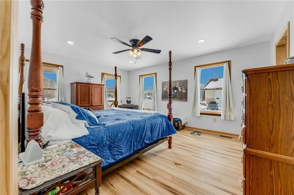 a bedroom with a bed a dresser and potted plants with wooden floor
