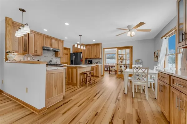 a kitchen with stainless steel appliances kitchen island granite countertop a table chairs and a refrigerator
