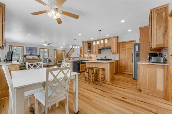 a kitchen with stainless steel appliances kitchen island granite countertop a refrigerator a stove a microwave oven a dining table and chairs with wooden floor