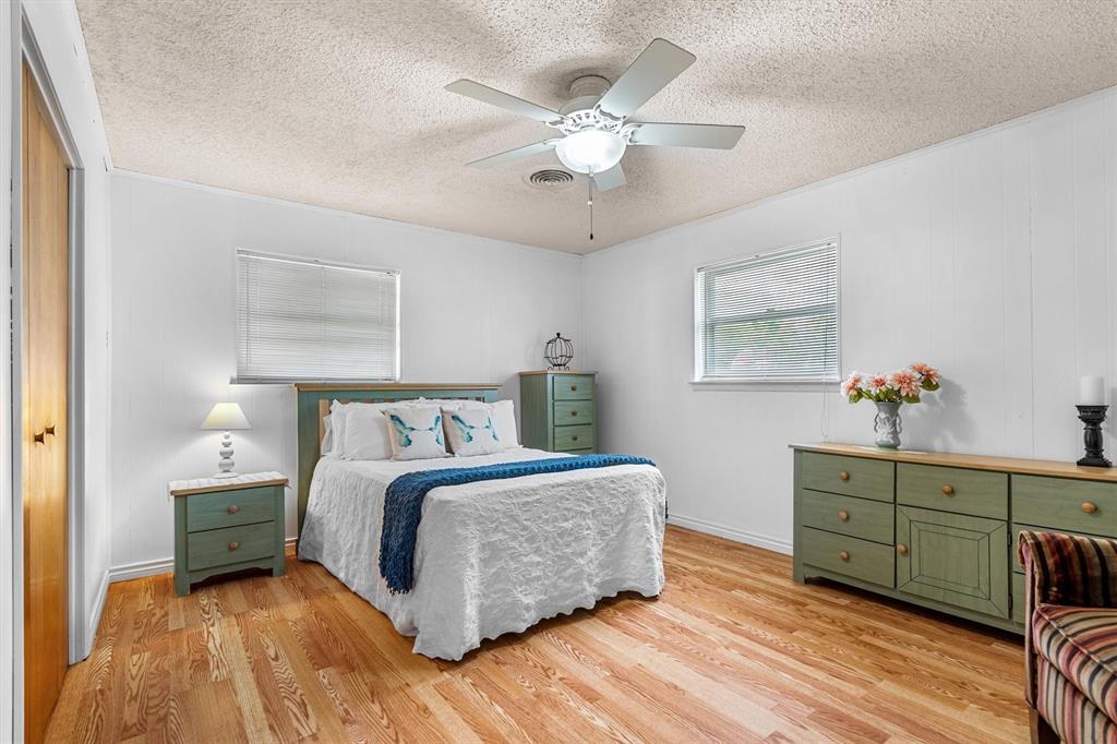 417 West 8th Street Justin, TX 76247 - Photo 17 of 40 a spacious bedroom with a bed and a chandelier