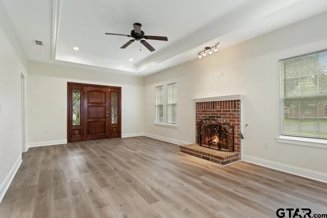 a view of an empty room with wooden floor ceiling fan and a window