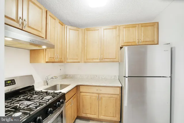 a kitchen with stainless steel appliances granite countertop a refrigerator stove sink and cabinets