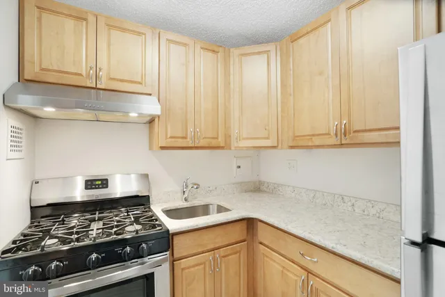 a kitchen with stainless steel appliances granite countertop a sink a stove and cabinets