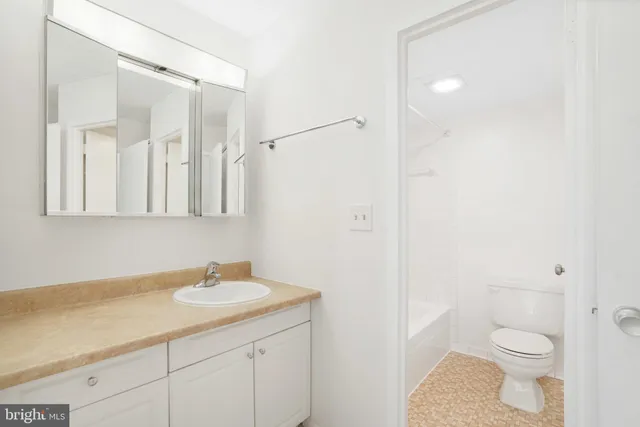 a bathroom with a granite countertop sink a toilet and a mirror