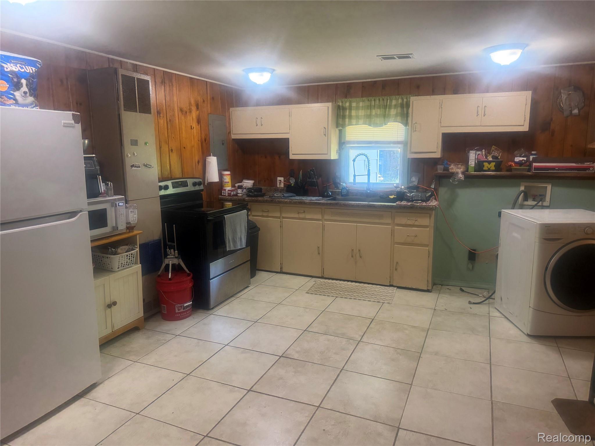5716 Falkenbury Road North Branch, MI 48461 - Photo 41 of 48 Kitchen featuring wood-panel walls, tile flooring, and cream-colored cabinetry