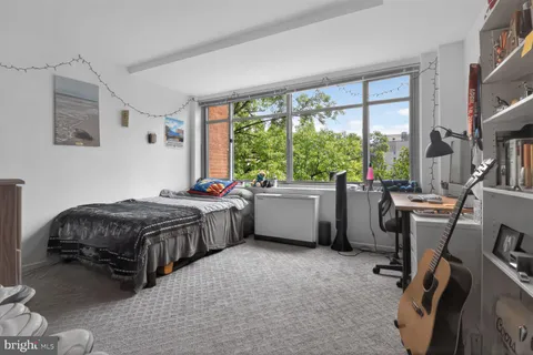 a bedroom with a bed dresser and a large window