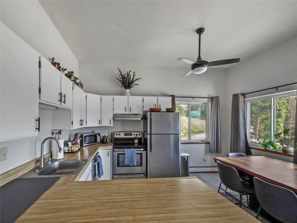 9876 Ryan Gulch Road, Unit 106 Silverthorne, CO 80498 - Photo 6 of 27 a kitchen with stainless steel appliances granite countertop a refrigerator a stove a sink dishwasher a oven with a dining table and chairs with wooden floor
