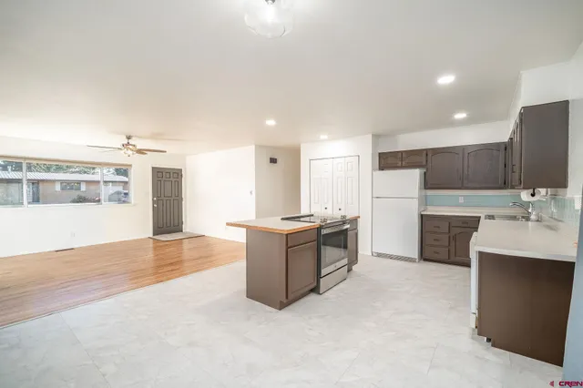 a large kitchen with a large counter top a sink stainless steel appliances and cabinets